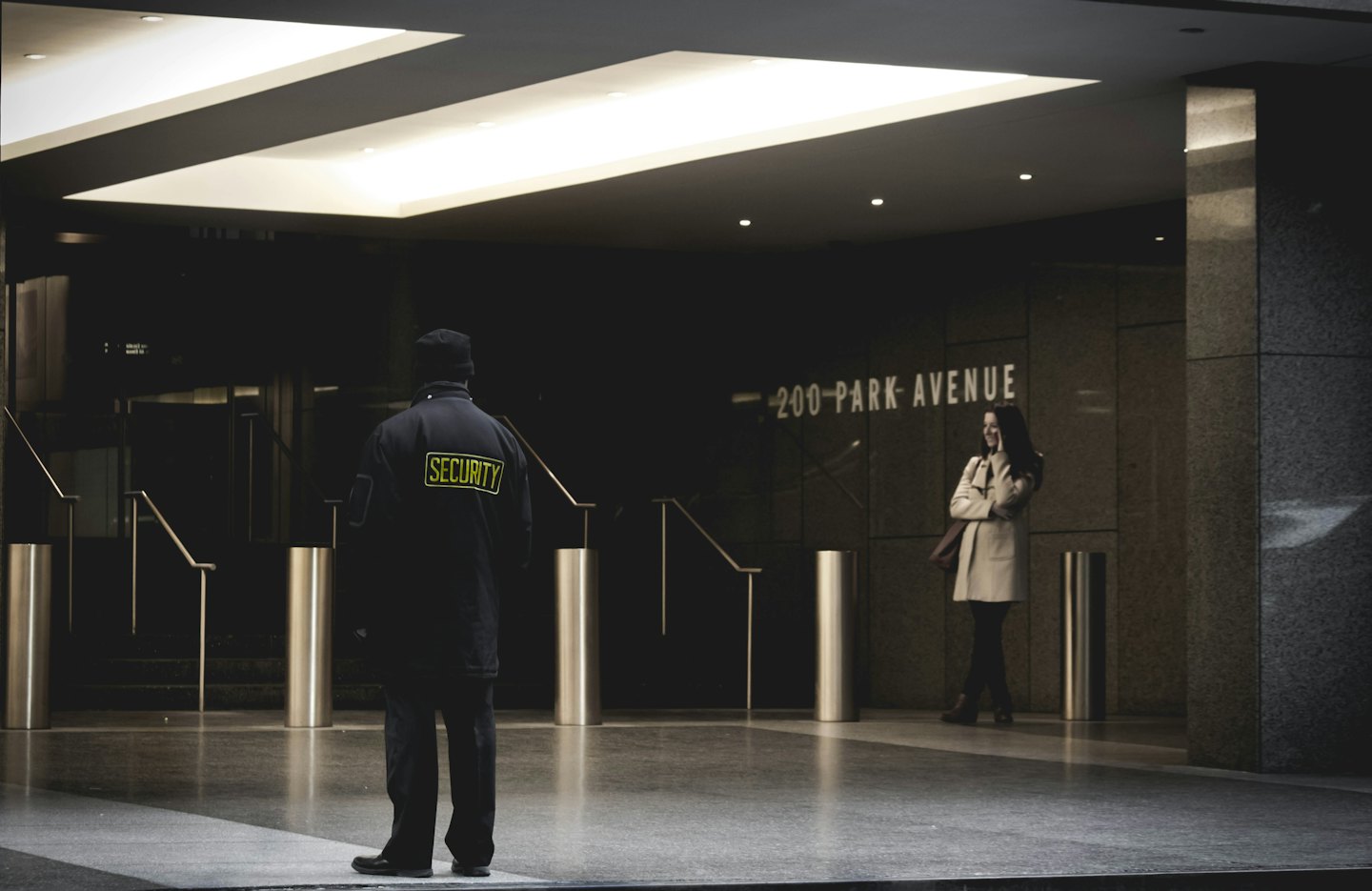 Eine Frau lächelt neben einem Wachmann am 200 Park Avenue.