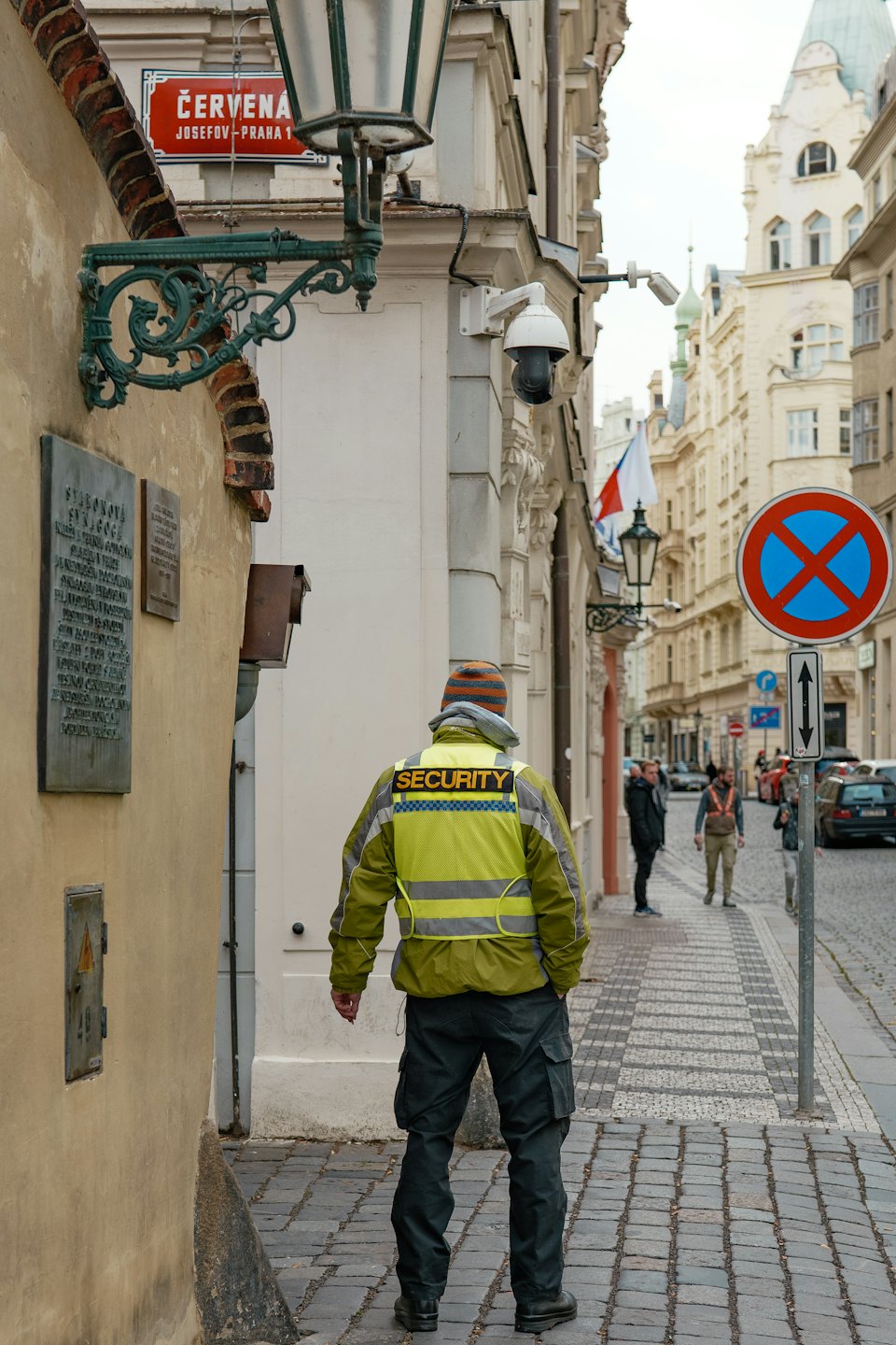 Ein Wachmann in einer Warnweste steht auf einer Kopfsteinpflasterstraße.